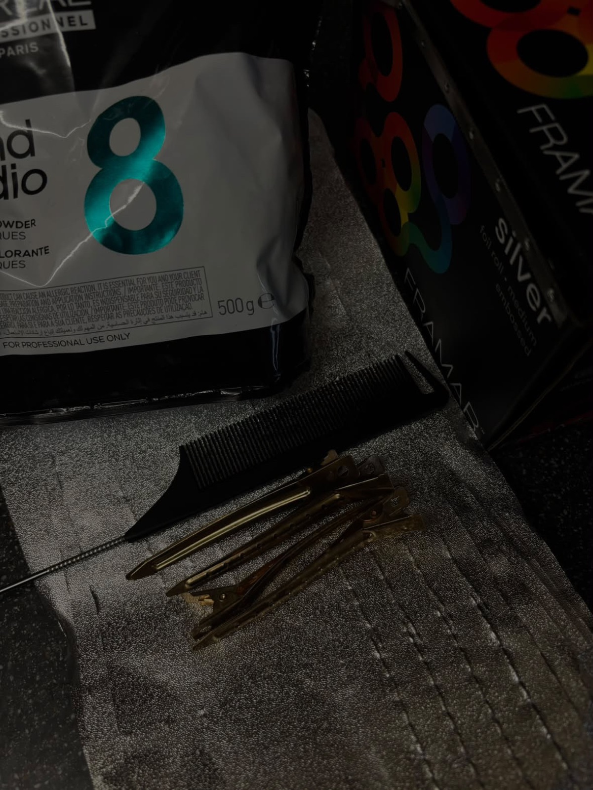 Lightener, foils, a tail comb and sectioning clips laid out before a colour service