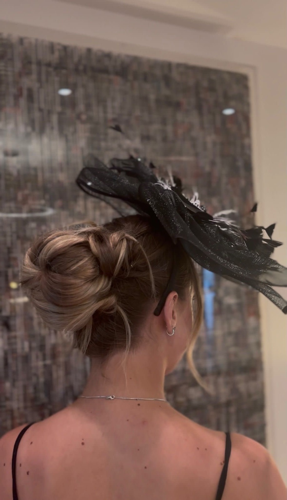 Textured blonde up-do styled for an occasion with a black fascinator